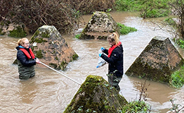Two UKCEH scientists in a river collecting samples