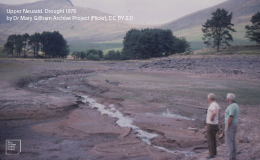 Two people stand on floor of dried up reservoir