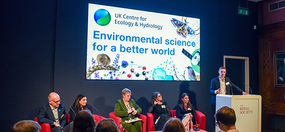 Chief executive Stuart Wainwright and panelists under a large screen saying Environmental science for a better world